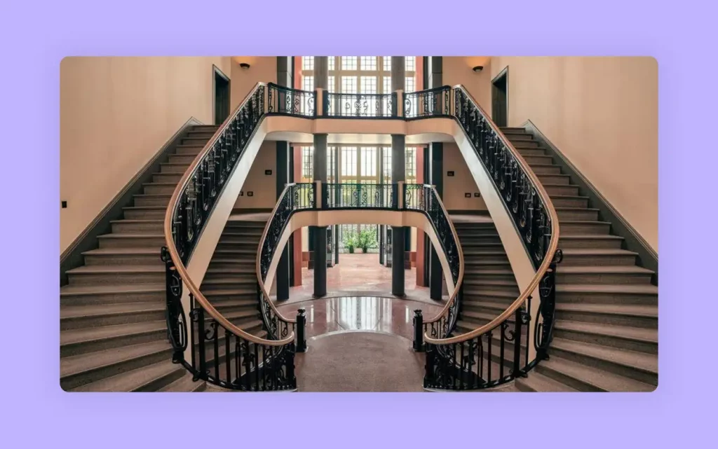 A grand U-shaped staircase with ornate railings in a large hall. 